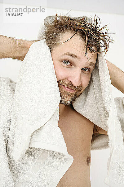 Lächelnder Mann trocknet zu Hause Haare mit Handtuch