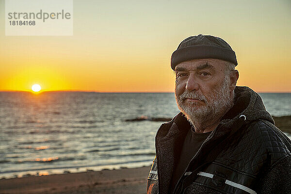 Rentner älterer Mann genießt Sonnenuntergang am Strand