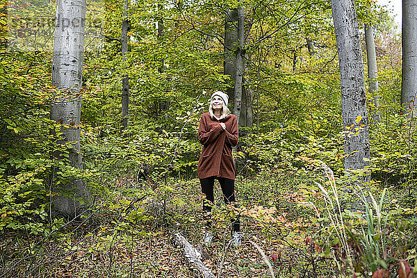 Reife Frau steht am Wochenende inmitten von Bäumen im Wald