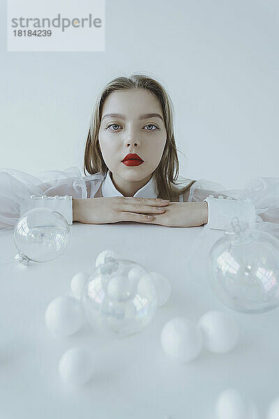 Girl with Christmas ornaments on table against white background