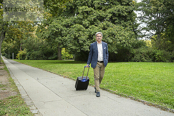 Geschäftsmann mit Gepäck läuft auf Fußweg