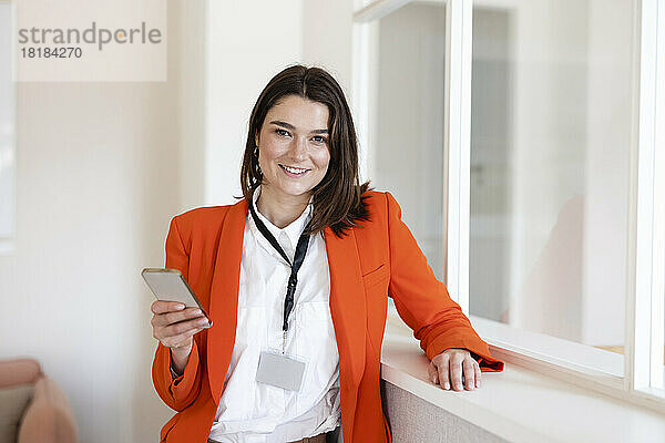 Glückliche Geschäftsfrau mit Mobiltelefon im Büro