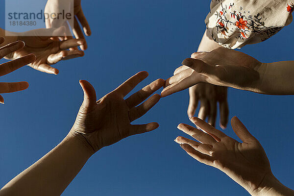 Hände von Frauen unter blauem Himmel