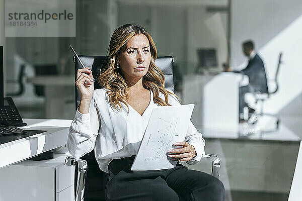 Nachdenkliche Geschäftsfrau sitzt mit Dokument im Büro