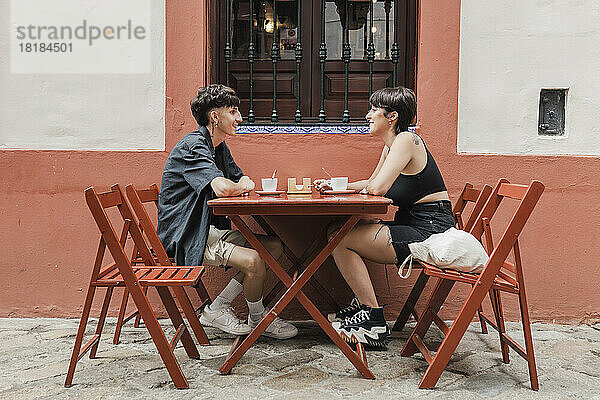 Lächelnder Mann unterhält sich mit Freundin im Straßencafé
