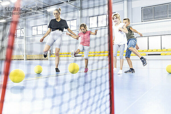 Lehrer und Schüler kicken Ball im Netz des Schulsportplatzes