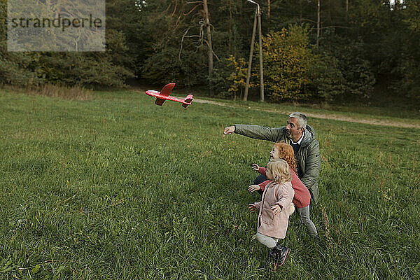 Großvater und Enkel spielen mit Flugzeugspielzeug auf Gras