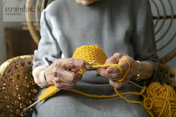 Hände einer älteren Frau  die zu Hause strickt