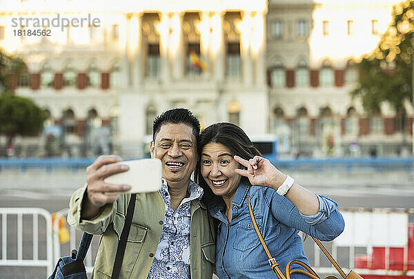 Lächelnder Mann und Frau machen auf dem Fußweg ein Selfie mit dem Mobiltelefon