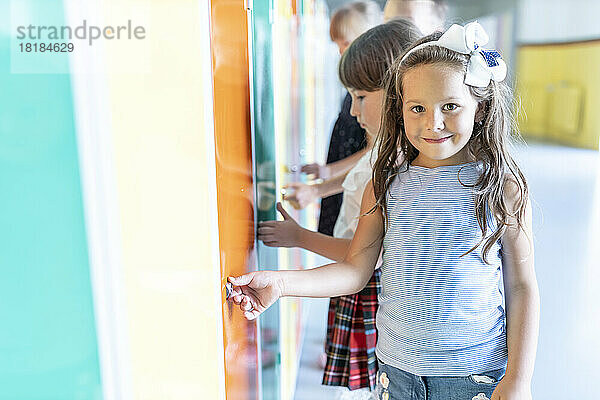 Smiling girl standing near lockers in school