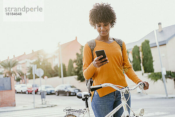 Frau mit Fahrrad benutzt Mobiltelefon auf der Straße