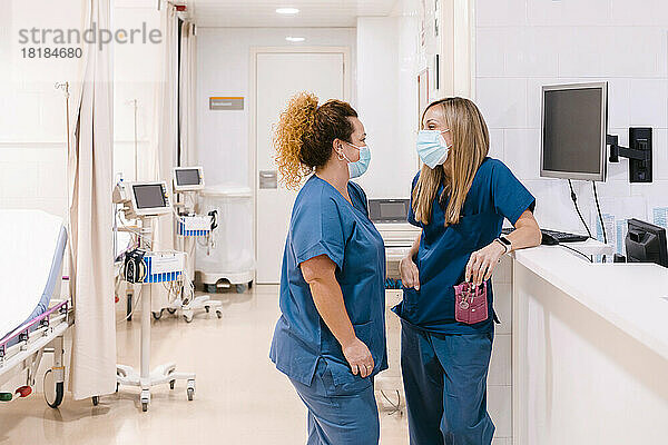 Reife Krankenschwester im Gespräch mit einem Kollegen im Krankenhaus