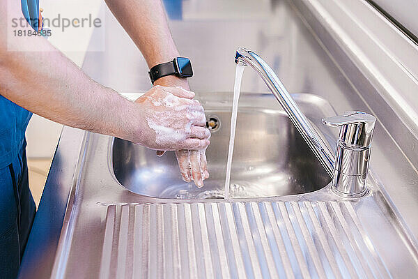 Arzt wäscht sich im Krankenhaus die Hände mit Wasser im Waschbecken