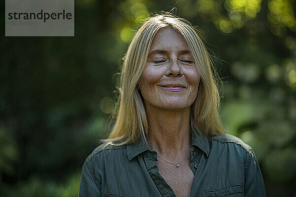 Smiling mature woman with eyes closed in garden