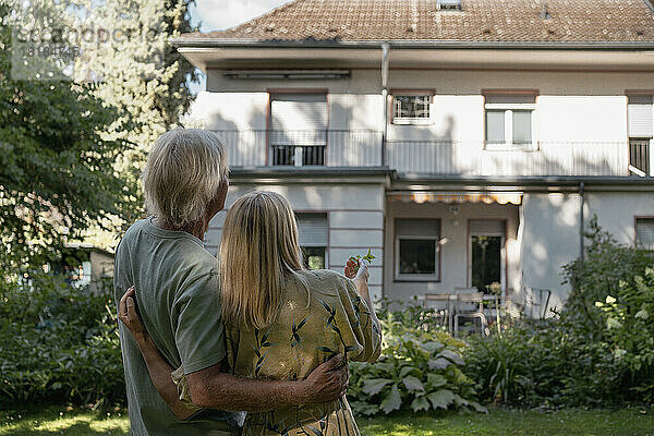 Paar steht zusammen und schaut auf das Haus