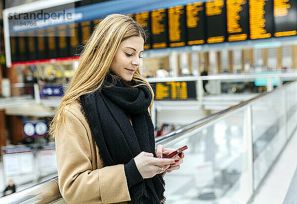 Großbritannien  London  junge Frau benutzt Mobiltelefon am Bahnhof