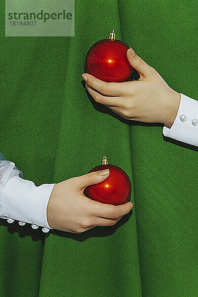 Hands of girl holding baubles embracing abstract Christmas tree