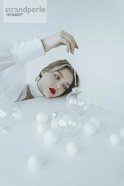 Girl holding transparent Christmas ball on white table