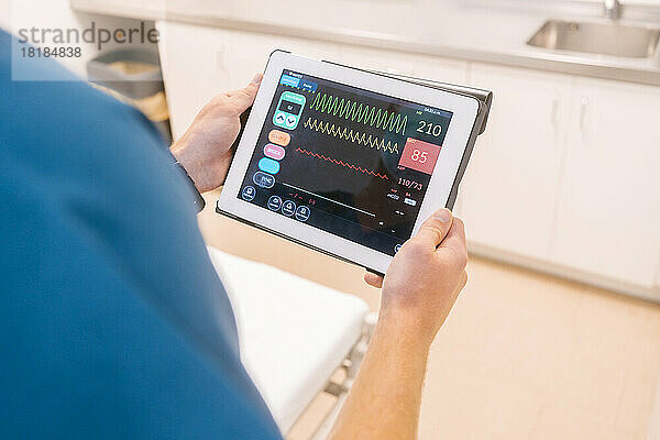 Hände eines Arztes untersuchen Daten auf einem Tablet-PC im Krankenhaus