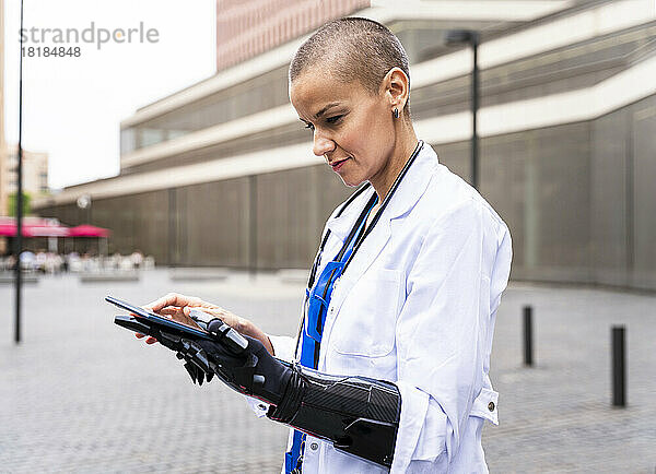 Arzt mit künstlicher Hand nutzt Tablet-PC auf Fußweg