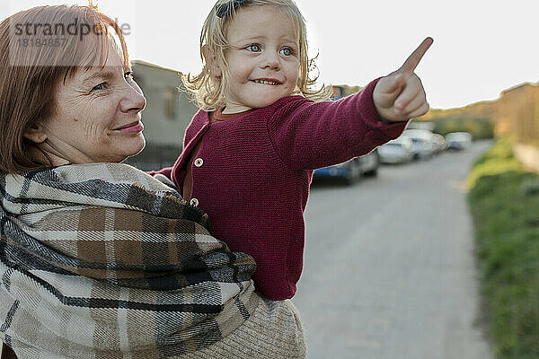Lächelnde Frau mit Enkelin gestikuliert auf Fußweg