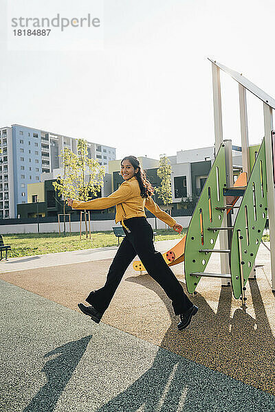 Lächelnde Frau  die an einem sonnigen Tag auf dem Spielplatz spaziert