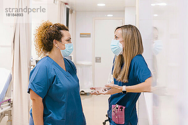 Krankenschwestern tragen Masken und reden im Krankenhaus miteinander