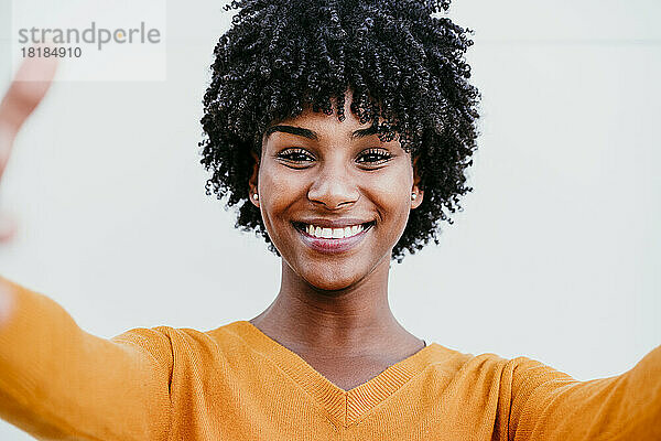 Lächelnde Frau mit Afro-Haaren macht ein Selfie
