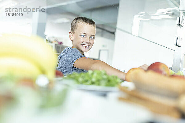 Smiling boy taking food at break time in cafeteria