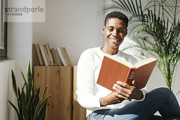Lächelnde Frau  die zu Hause ein Buch liest