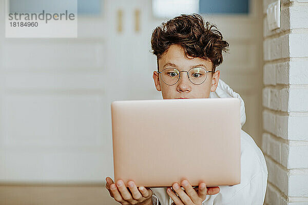 Schockierter Junge mit Laptop zu Hause