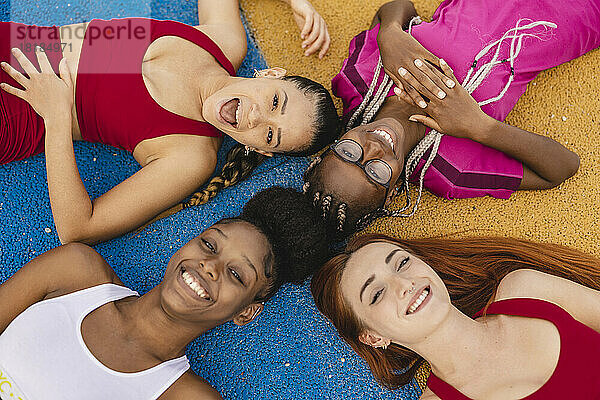 Cheerful friends lying down in sports court