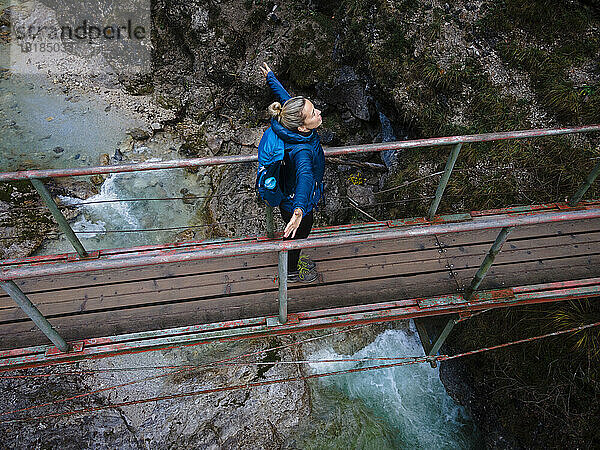 Austria  Lower Austria  Annaberg  Drone view of female hiker standing with raised arms on bridge stretching over Otscherbach river