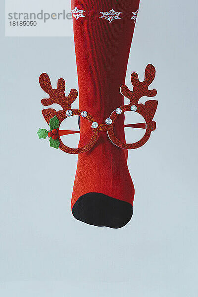 Bein eines Mädchens mit roter Weihnachtssocke und Brille aus Rentiergeweih
