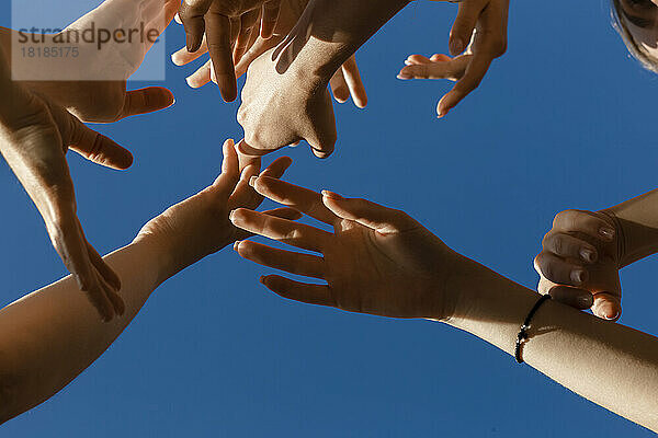 Hände junger Frauen unter blauem Himmel