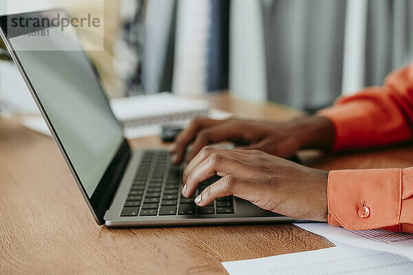 Hände einer jungen Geschäftsfrau  die Laptop am Schreibtisch benutzt