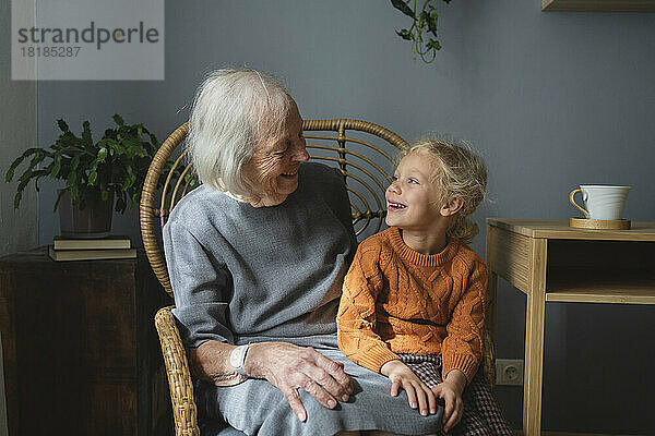 Glückliche Großmutter und Enkelin schauen sich auf einem Stuhl an