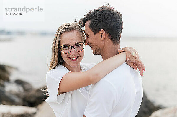 Smiling woman embracing boyfriend at beach