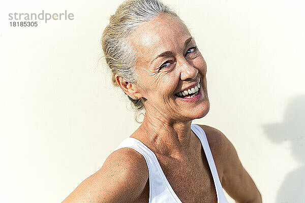 Happy mature woman in front of cream colored wall