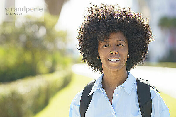 Fröhlicher Student mit Afro-Frisur an einem sonnigen Tag