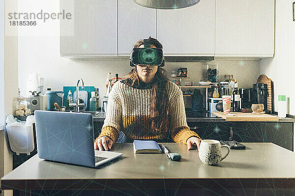 Frau mit Virtual-Reality-Brille sitzt vor Laptop im Heimbüro