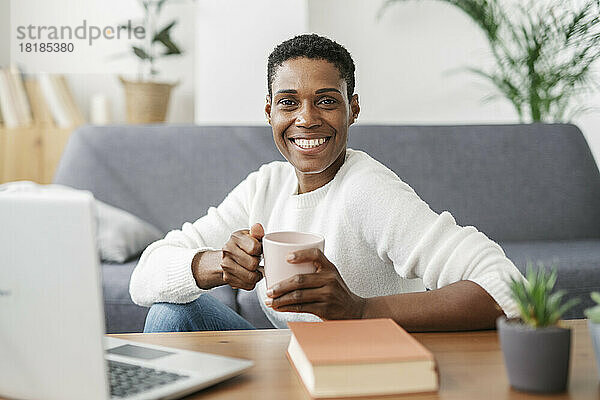 Porträt einer lächelnden Frau mit einer Tasse Kaffee in einem liebevollen Zimmer zu Hause