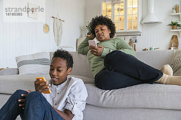 Mutter und Sohn nutzen zu Hause Smartphones