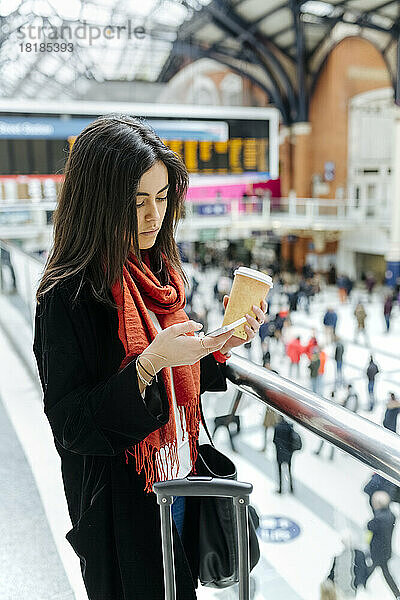 Großbritannien  London  junge Frau benutzt Mobiltelefon am Bahnhof