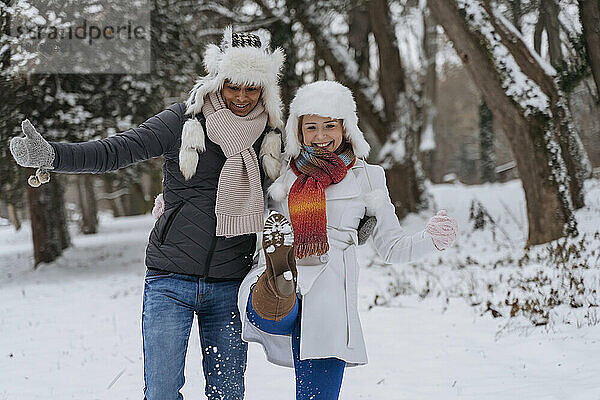 Glücklicher junger Mann mit Frau  die im Schnee spielt