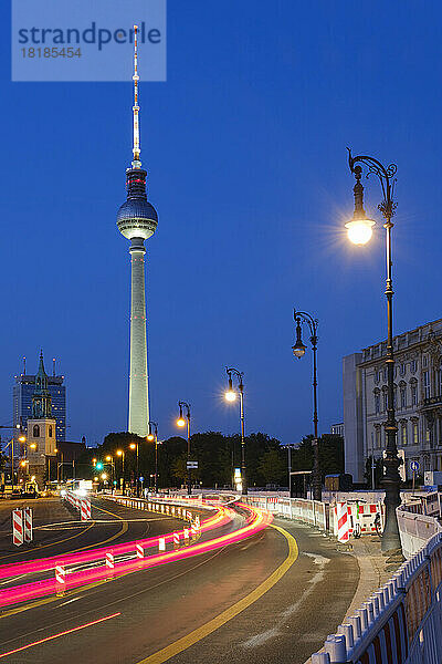 Germany  Berlin  Vehicle light trails stretching along illuminated street at night with Berlin Television Tower in background