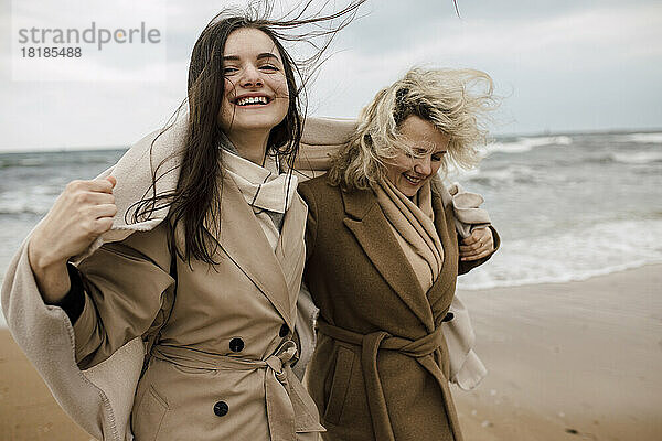 Mutter und Tochter tragen Mäntel und genießen den Strand
