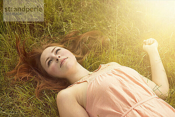 Daydreaming woman lying on a meadow