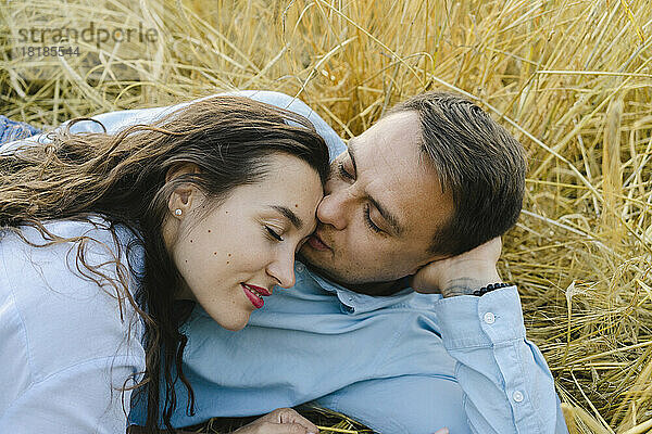 Smiling woman leaning on man lying in field