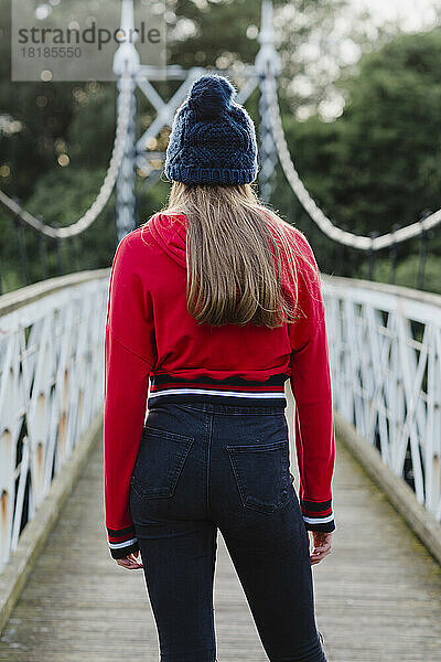 Rückansicht eines Teenager-Mädchens auf einer Brücke  roter Kapuzenpullover